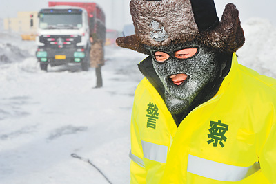 12月23日，新疆一交警在帮助被“风吹雪”围困的车辆脱困。